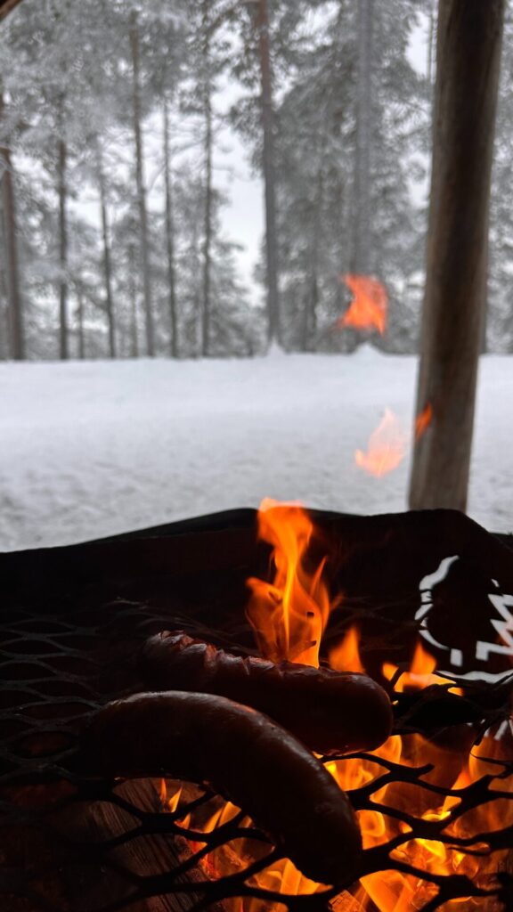 Rentierwurst brät auf Rost am Lagerfeuer Winter Finnland