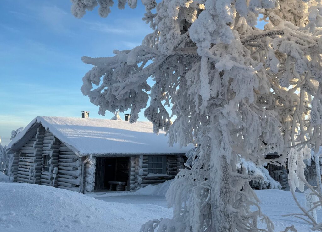 Schnee Hütte eingeschneite Bäume blauer Himmel Lappland kalt
