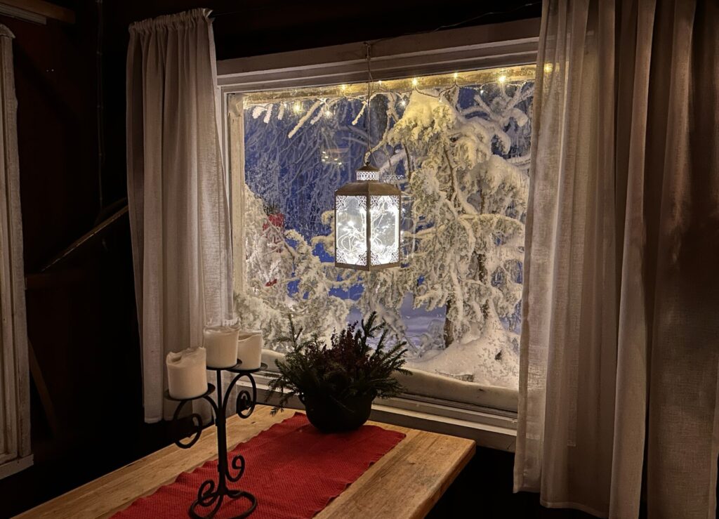 Blick durch Fenster mit Laterne auf verschneite Bäume